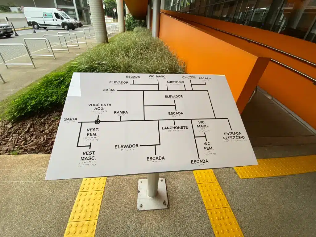 Edifício com mapa em braile e pisos táteis amarelos, como piso alerta ou direcional.